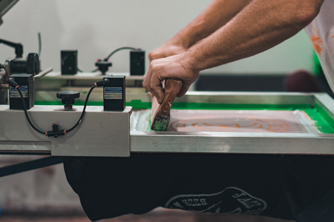 A print shop worker operating a screen printing machine